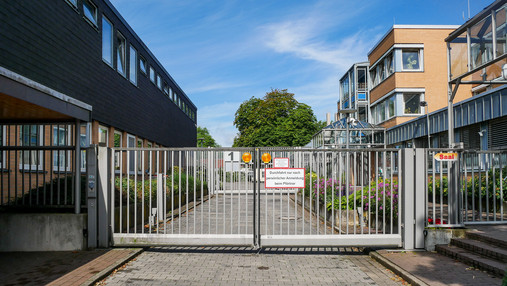 Maßregelvollzug Moringen - Zufahrt Foto zum Thema "Maßregelvollzug Moringen": Zu sehen ist die Zufahrt zum Gelände, die durch ein hohes Gatter versperrt ist.