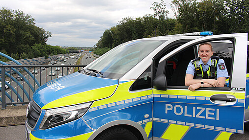 Foto zum Thema "Wie wird man Polizist*in": Zu sehen ist Svenja, die in der Tür des Streifenwagens steht.