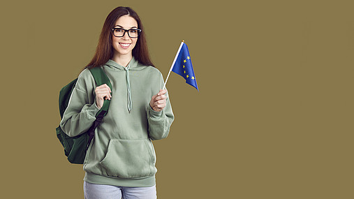 Junge Frau schwenkt eine kleine Europa-Flagge. 