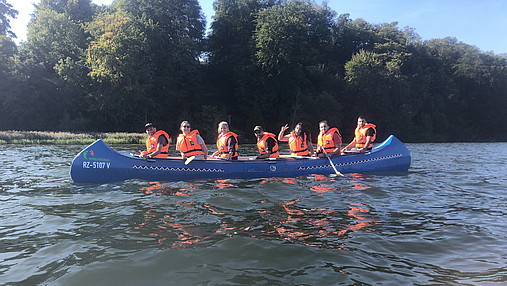 Das Foto zeigt eine Gruppe im Kanu auf dem Wasser.