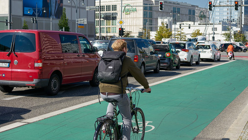 Radfahrende Person auf einem grün markierten Radweg in einer Stadt