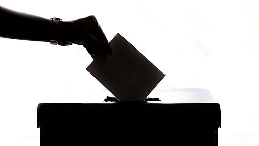 Foto zum Thema neues Wahlrecht zur Bundestagswahl: Zu sehen ist eine Hand mit einem Stimmzettel über einer Wahlurne.
