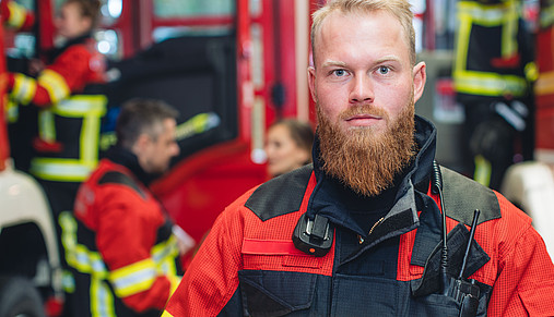 Junger Mitarbeiter des Rettungsdienstes einer Feuerwehr, der entschlossen in die Kamera blickt. 