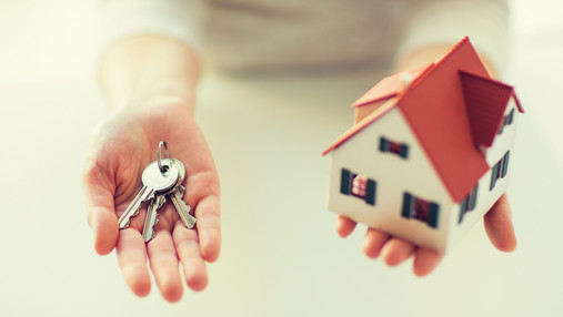 Immobilienfinanzierung - worauf es ankommt Foto zum Thema "immobilienfinanzierung dbb vorsorgewerk": Zu sehen sind zwei Hände. Die linke hält Haustürschlüssel, die rechte ein Modellhaus.