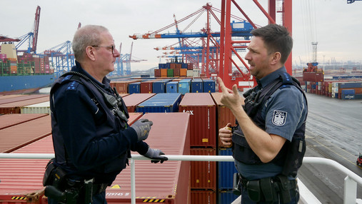 Foto zum Thema „Zoll Hamburger Hafen“: Zu sehen sind Felix und Tom, die beiden Zollbeamten, die #staatklar begleitet hat. Sie stehen an Deck eines Containerschiffes.