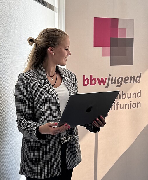 Das Foto zeigt Maxi Schröder mit einem Laptop in der Hand.