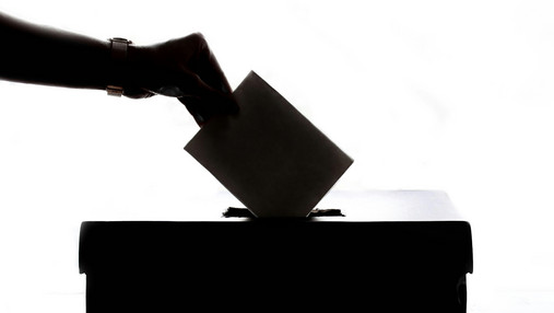 Foto zum Thema neues Wahlrecht zur Bundestagswahl: Zu sehen ist eine Hand mit einem Stimmzettel über einer Wahlurne.