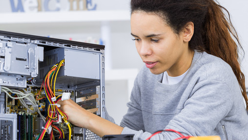 Eine junge Auszubildende arbeitet an einem geöffneten PC.