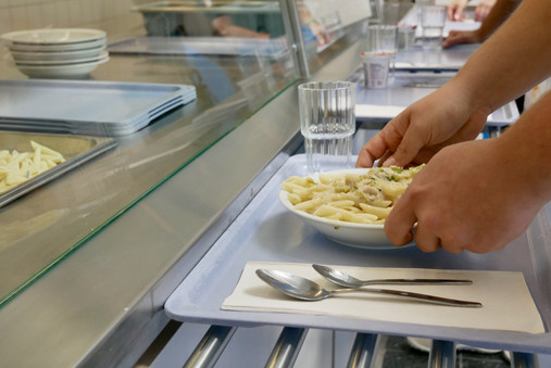 JVA Hahnöfersand - Essen Foto zum Thema "JVA Hahnöfersand": Zu sehen ist eine Nahaufnahme bei der Essensausgabe. Abgebildet ist ein Tablet mit Pasta und Besteck, die Hände eines Gefangenen sind ebenfalls zu sehen.