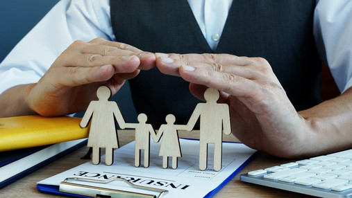 Agent protects family figures. Life Insurance policy on a desk.